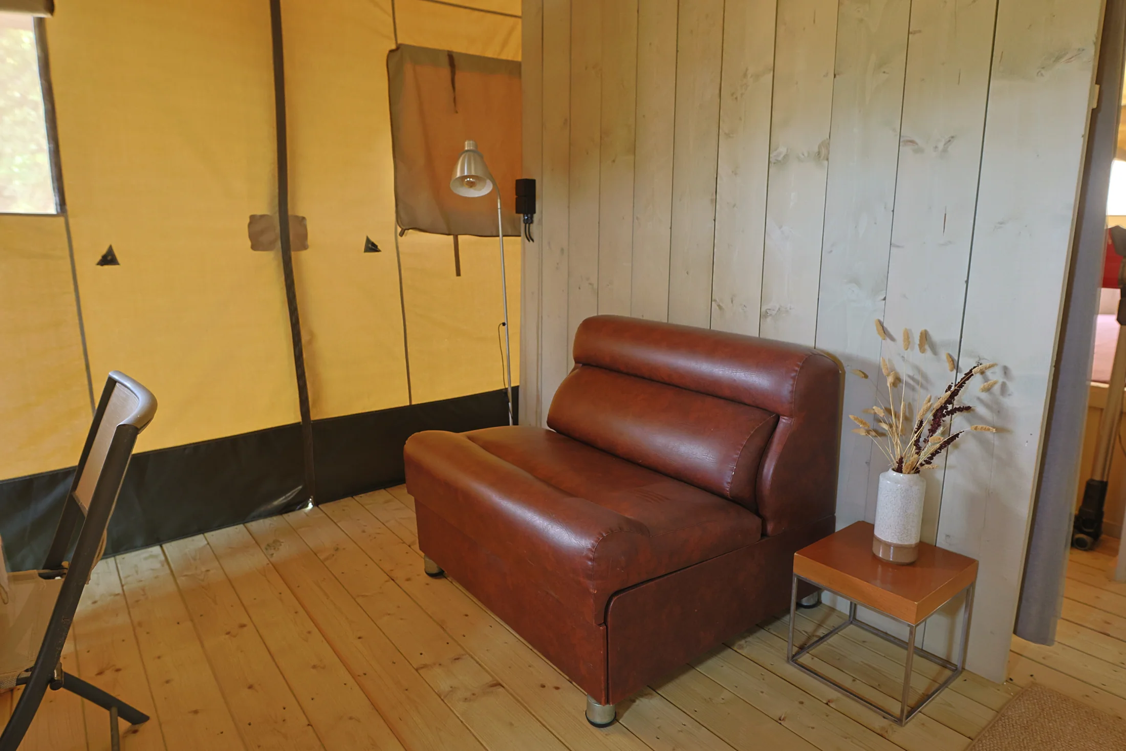 Interno del glamping con la poltrona nel salottino in legno e tela